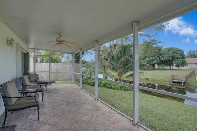 sunroom featuring ceiling fan and a water view