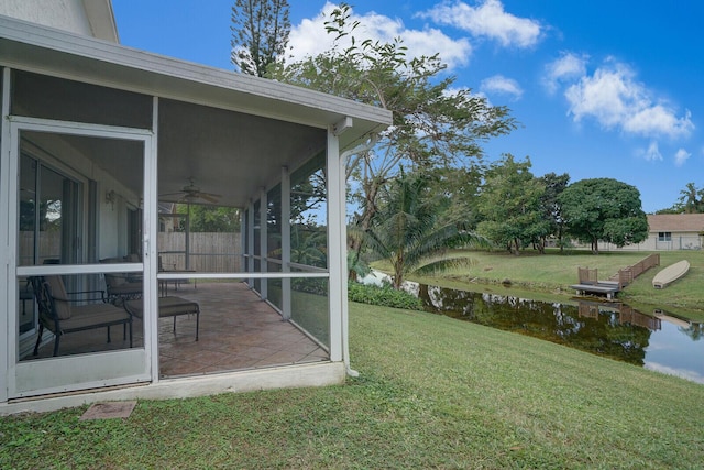 view of yard featuring a sunroom, a water view, and a patio