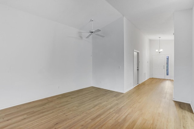 unfurnished room featuring ceiling fan with notable chandelier, high vaulted ceiling, and light hardwood / wood-style flooring