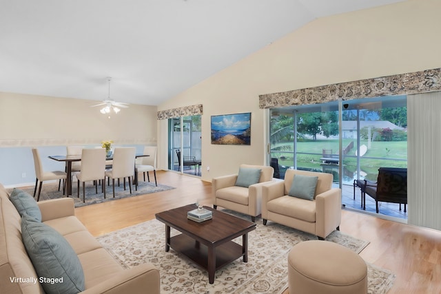 living room with ceiling fan, light hardwood / wood-style floors, a wealth of natural light, and vaulted ceiling