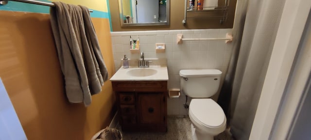 bathroom with vanity, toilet, and tile walls