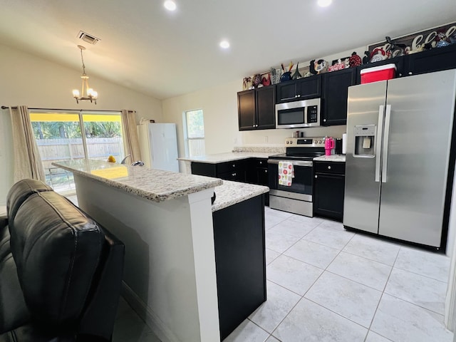 kitchen featuring lofted ceiling, decorative light fixtures, a kitchen island, a wealth of natural light, and stainless steel appliances