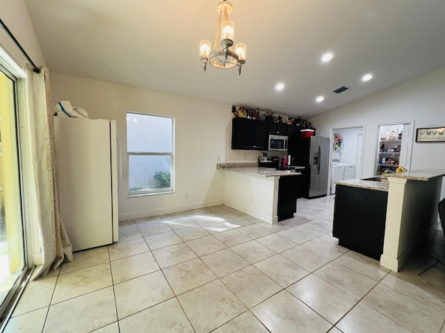 kitchen featuring vaulted ceiling, appliances with stainless steel finishes, hanging light fixtures, kitchen peninsula, and light stone countertops