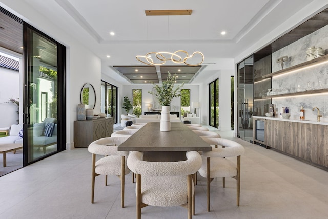 dining area featuring a tray ceiling, indoor wet bar, plenty of natural light, and beverage cooler