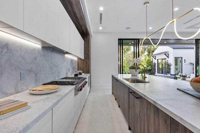 kitchen featuring white cabinets, dark brown cabinets, pendant lighting, and sink