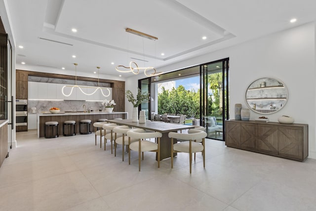 dining area featuring a raised ceiling and a chandelier