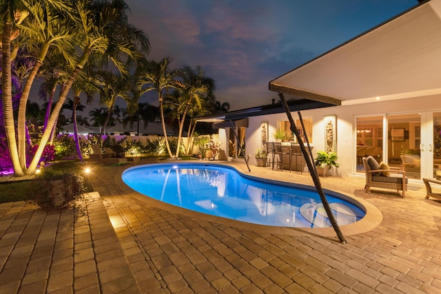 pool at dusk with a patio area