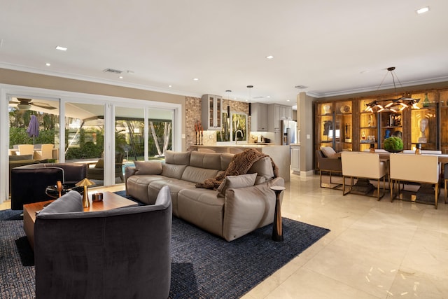 living room featuring ceiling fan with notable chandelier, crown molding, and sink