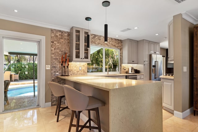 kitchen with sink, hanging light fixtures, appliances with stainless steel finishes, kitchen peninsula, and a breakfast bar area