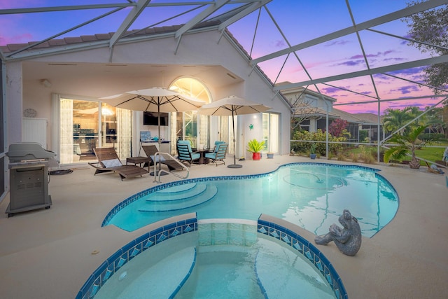 pool at dusk featuring an in ground hot tub, a patio, and a lanai