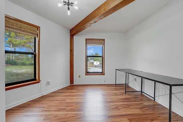 empty room with beamed ceiling, a chandelier, and light hardwood / wood-style flooring