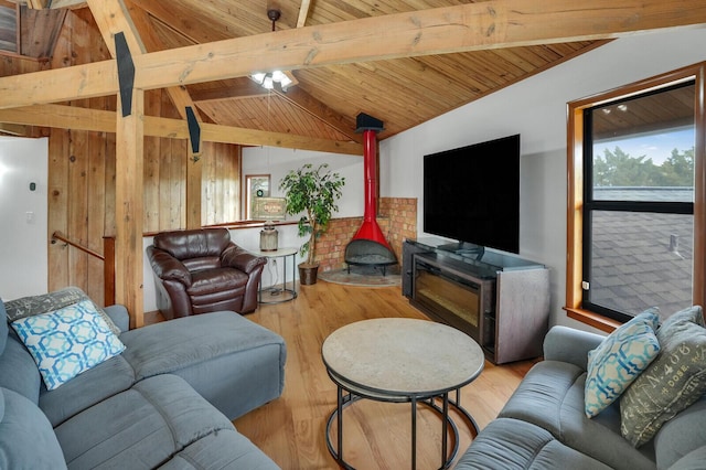 living room featuring a wood stove, wooden ceiling, lofted ceiling with beams, wood walls, and light wood-type flooring