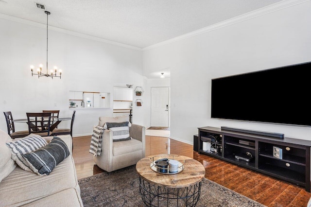 living room featuring ornamental molding, dark wood-type flooring, a textured ceiling, and an inviting chandelier