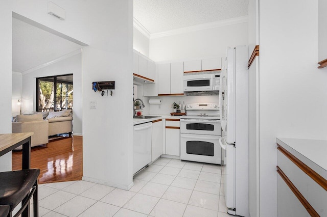 kitchen featuring white appliances, white cabinets, sink, light tile patterned floors, and a textured ceiling