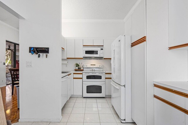 kitchen featuring ornamental molding, white appliances, a textured ceiling, light tile patterned floors, and white cabinets