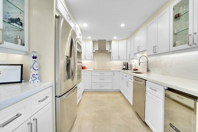 kitchen featuring backsplash, wall chimney exhaust hood, stainless steel appliances, sink, and white cabinetry