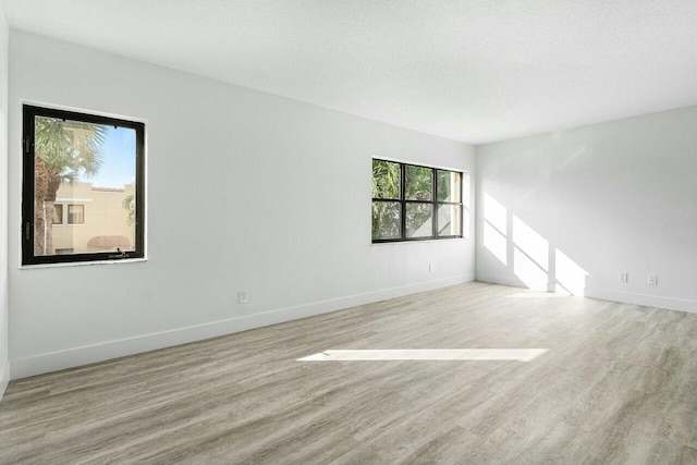 empty room with light hardwood / wood-style flooring and a textured ceiling