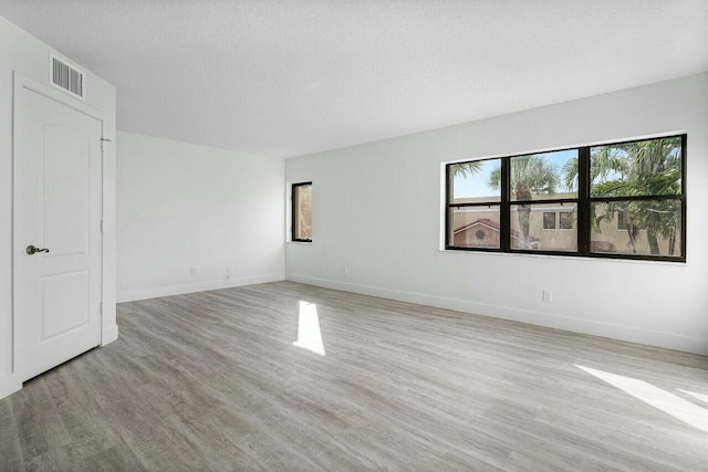 unfurnished room with a textured ceiling and light wood-type flooring