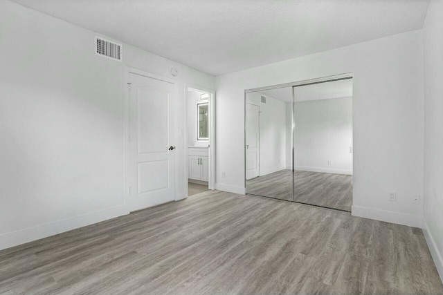 unfurnished bedroom featuring light hardwood / wood-style floors and a closet