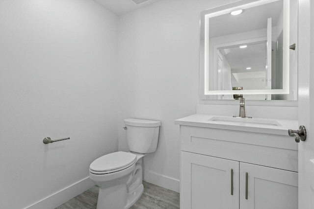 bathroom with hardwood / wood-style flooring, vanity, and toilet