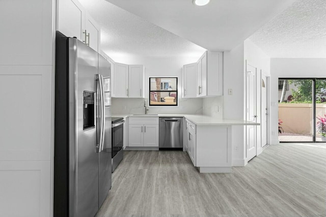 kitchen featuring light hardwood / wood-style floors, a textured ceiling, decorative backsplash, white cabinets, and appliances with stainless steel finishes