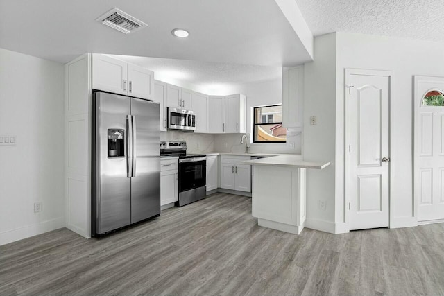 kitchen featuring white cabinetry, appliances with stainless steel finishes, plenty of natural light, and light wood-type flooring