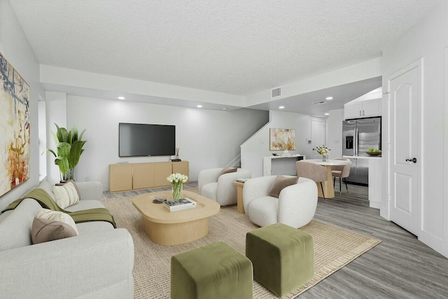 living room with a textured ceiling and light hardwood / wood-style floors