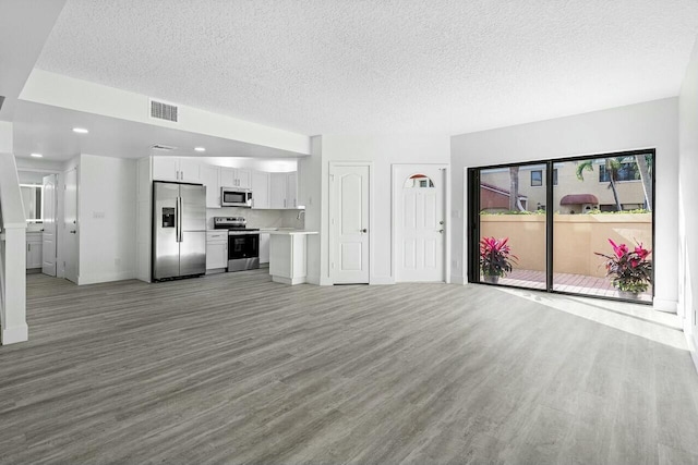 unfurnished living room with light hardwood / wood-style flooring and a textured ceiling