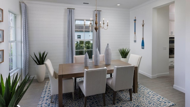 dining space with crown molding, an inviting chandelier, and light wood-type flooring