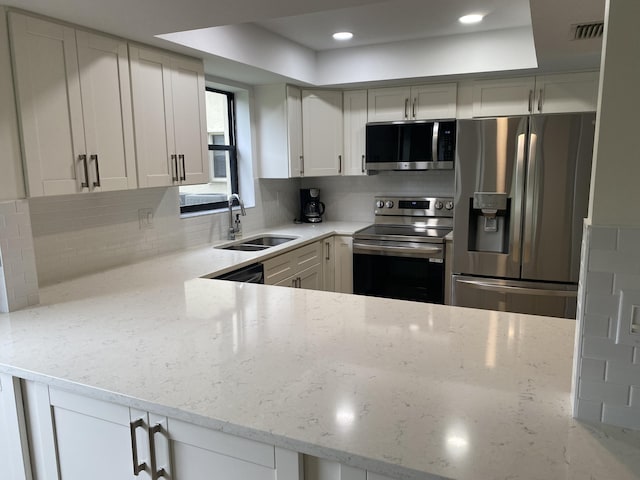 kitchen featuring appliances with stainless steel finishes, tasteful backsplash, light stone counters, sink, and white cabinets