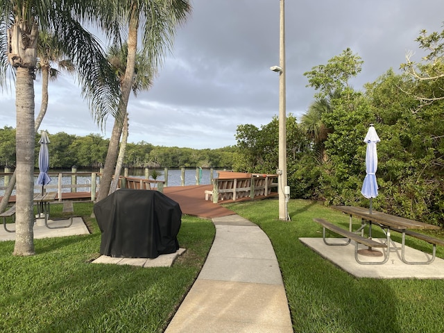 surrounding community featuring a water view, a lawn, and a boat dock