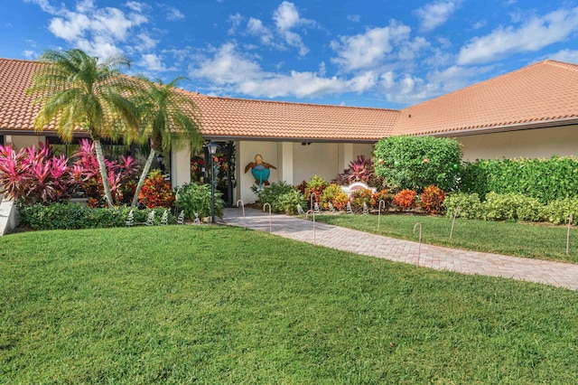 mediterranean / spanish house with stucco siding, a tiled roof, and a front lawn