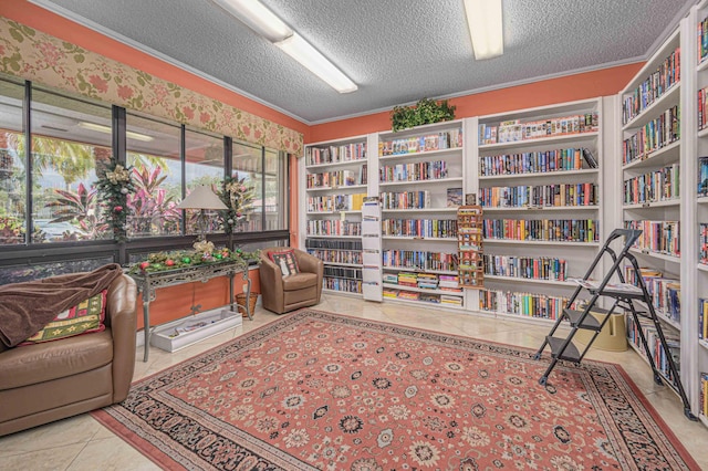 sitting room with bookshelves, tile patterned flooring, a textured ceiling, and ornamental molding