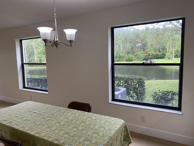 bedroom with an inviting chandelier, baseboards, and a water view