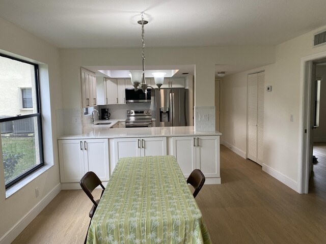 kitchen featuring dishwasher, decorative backsplash, light wood-style floors, white cabinets, and a sink