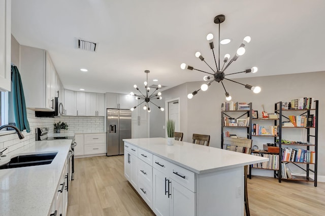 kitchen featuring pendant lighting, a notable chandelier, white cabinets, and appliances with stainless steel finishes