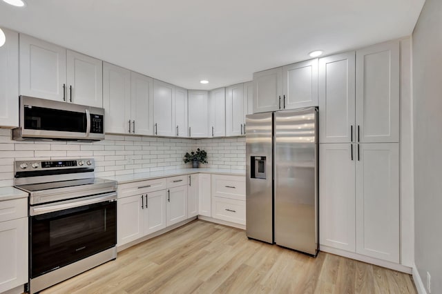 kitchen featuring appliances with stainless steel finishes, light hardwood / wood-style flooring, and white cabinetry