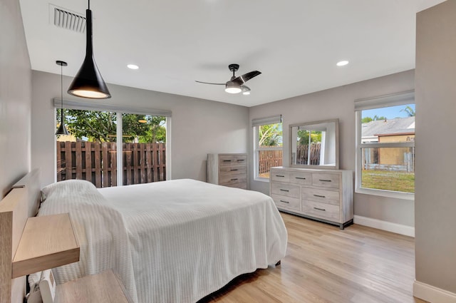 bedroom featuring ceiling fan, light hardwood / wood-style floors, and multiple windows