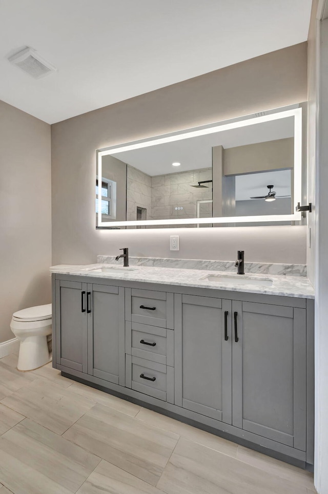 bathroom featuring vanity, ceiling fan, a shower, and toilet