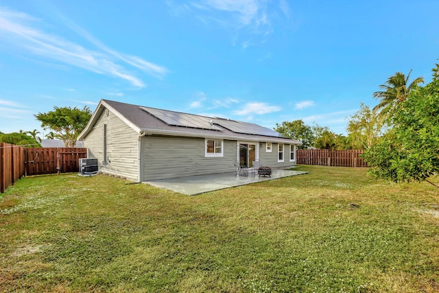 back of property featuring a patio area, a yard, cooling unit, and solar panels