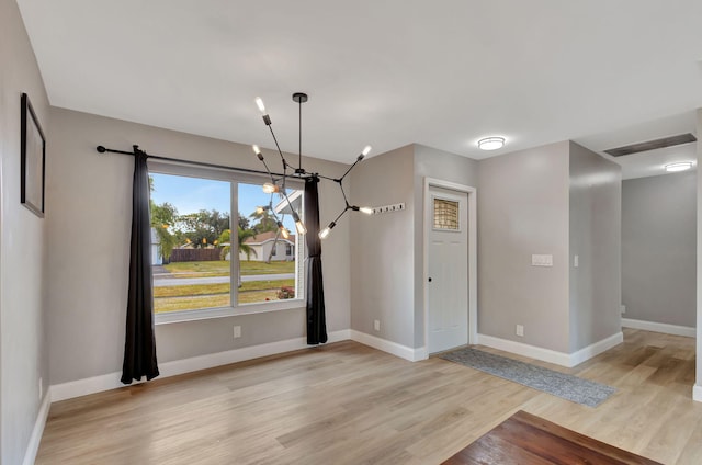 unfurnished dining area with light hardwood / wood-style flooring and a notable chandelier