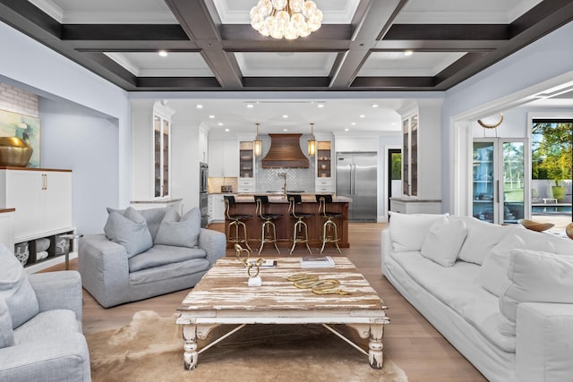 living room with coffered ceiling, an inviting chandelier, and beamed ceiling