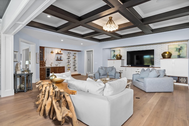 living room with beverage cooler, beamed ceiling, an inviting chandelier, light hardwood / wood-style flooring, and coffered ceiling