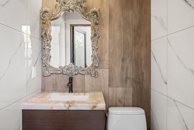 bathroom featuring tile walls, toilet, and vanity