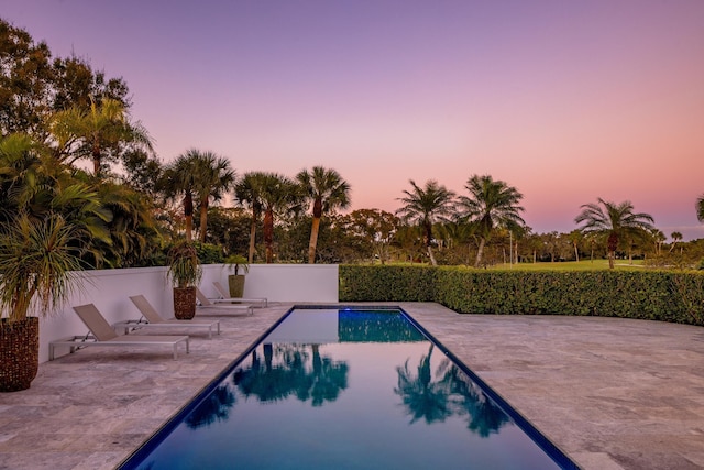 pool at dusk featuring a patio