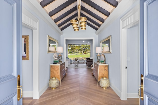 hall with a notable chandelier, vaulted ceiling with beams, and hardwood / wood-style floors