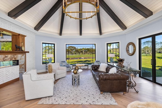 living room featuring high vaulted ceiling, light hardwood / wood-style floors, beam ceiling, and a stone fireplace