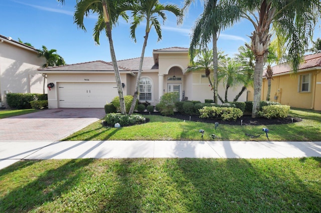 mediterranean / spanish-style home featuring a garage and a front lawn