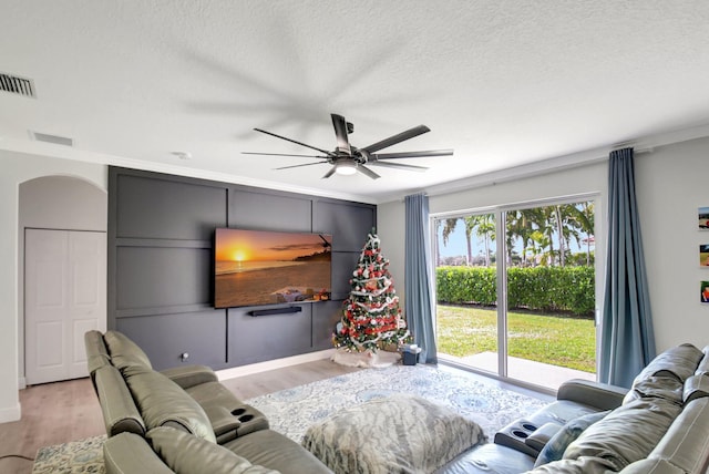 living room with crown molding, ceiling fan, light hardwood / wood-style floors, and a textured ceiling