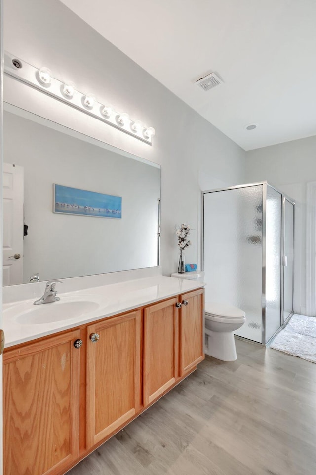 bathroom featuring hardwood / wood-style floors, vanity, a shower with door, and toilet